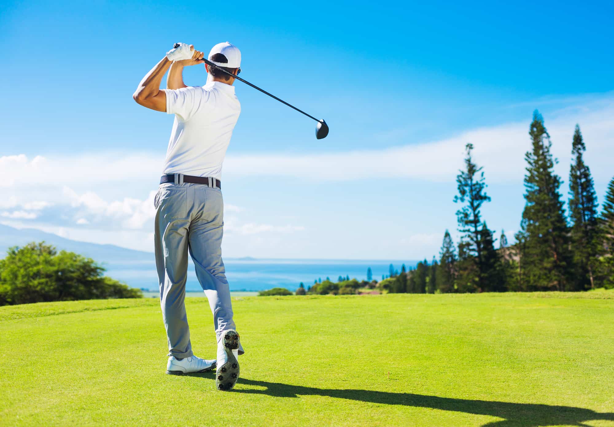 Golfer Hitting Ball with Club on Beautiful Golf Course