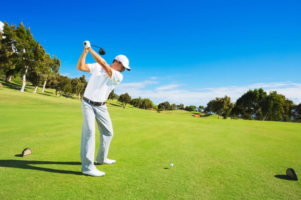 Golfspieler beim Abschlag. Mann schlägt Golfball von Tee-Box mit Fahrer.