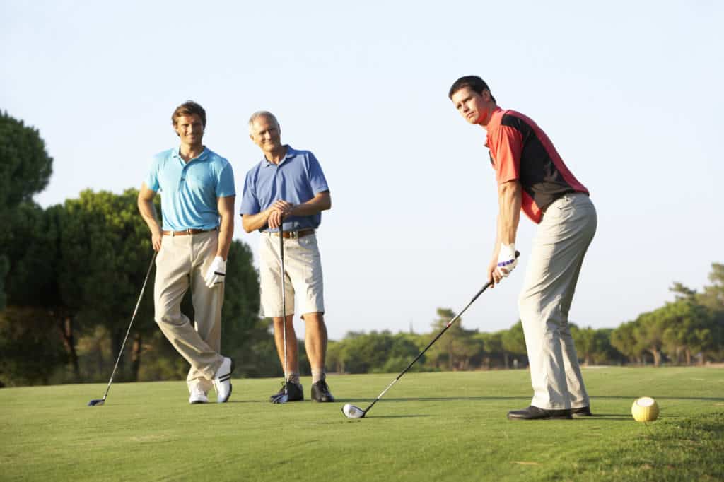 Group Of Male Golfers Teeing Off On Golf Course