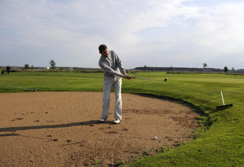 Golf player make a sand shot