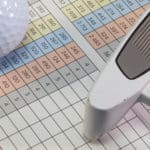 Golf putter and other equipments lying on a golf score card