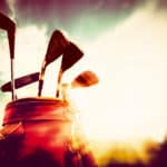 Golf clubs in a leather baggage in vintage, retro style at sunset