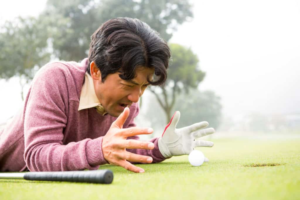 Golfer lying near golf ball at golf course