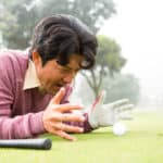Golfer lying near golf ball at golf course