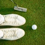 One shot to success. Top view of golfer staying near white ball, holding driver