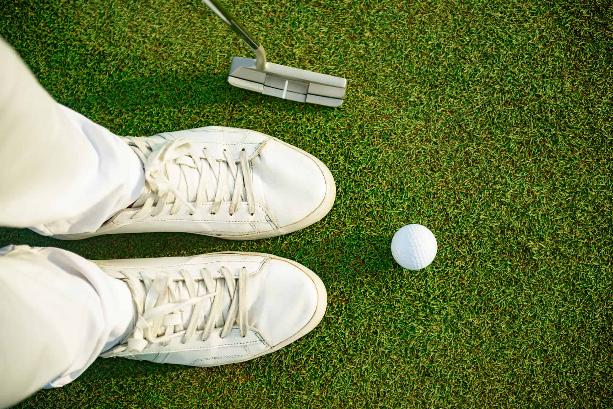 One shot to success. Top view of golfer staying near white ball, holding driver