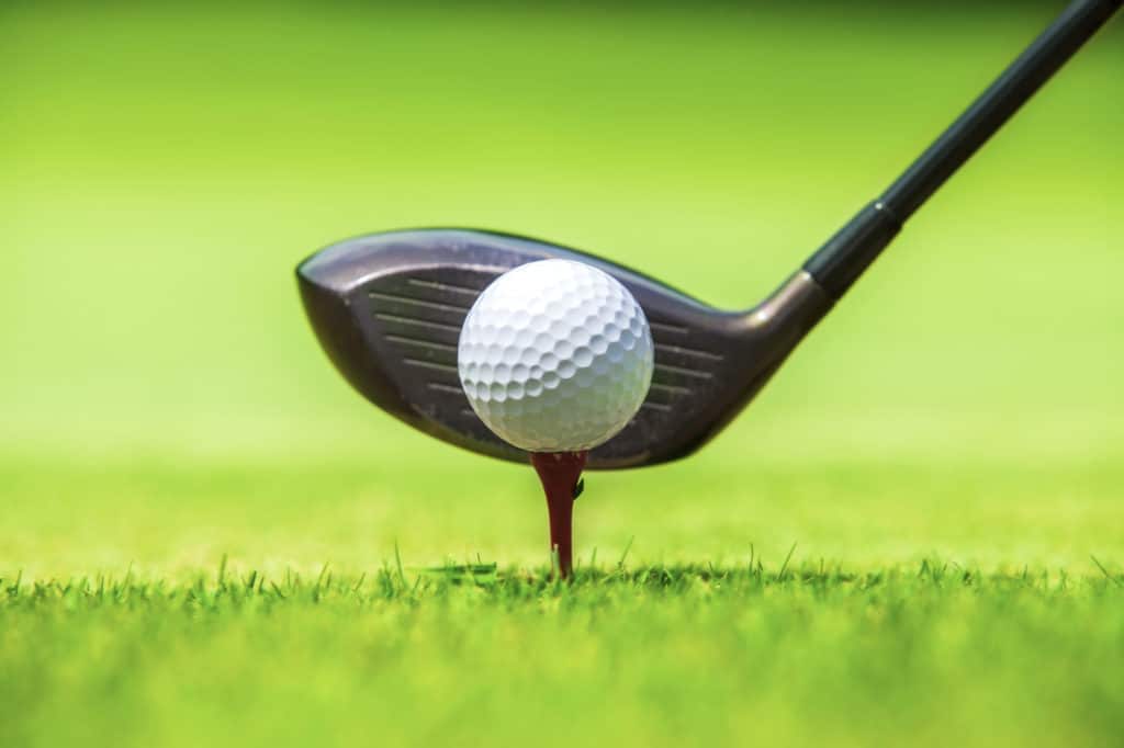 Golf ball behind driver at driving range