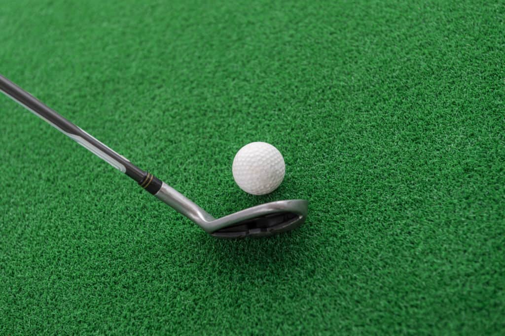 Golf club and ball on a golf mat