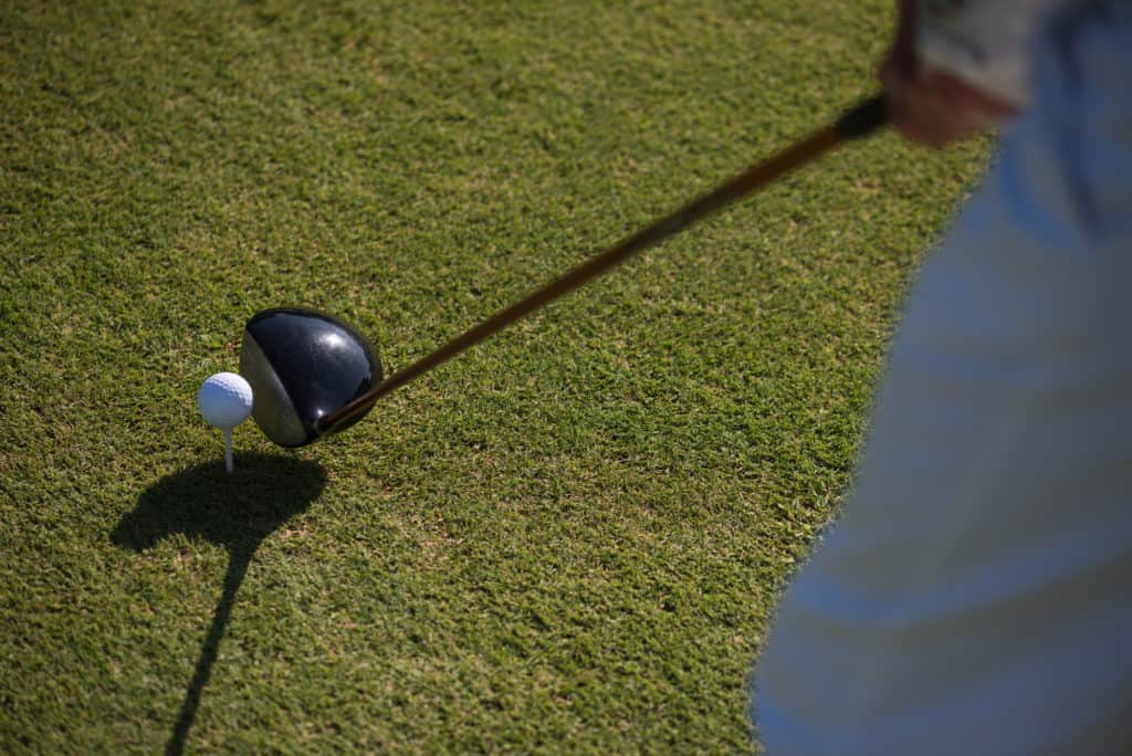 top view of golf club and ball in grass