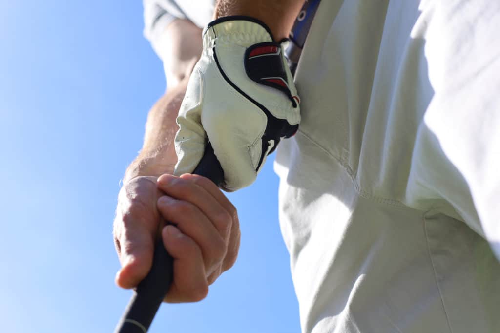 Golfer wearing a golf holding a putter.