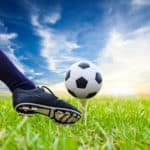 foot kicking soccer ball on golf tee