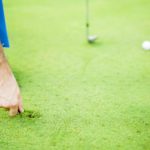 Golf player repairing divot