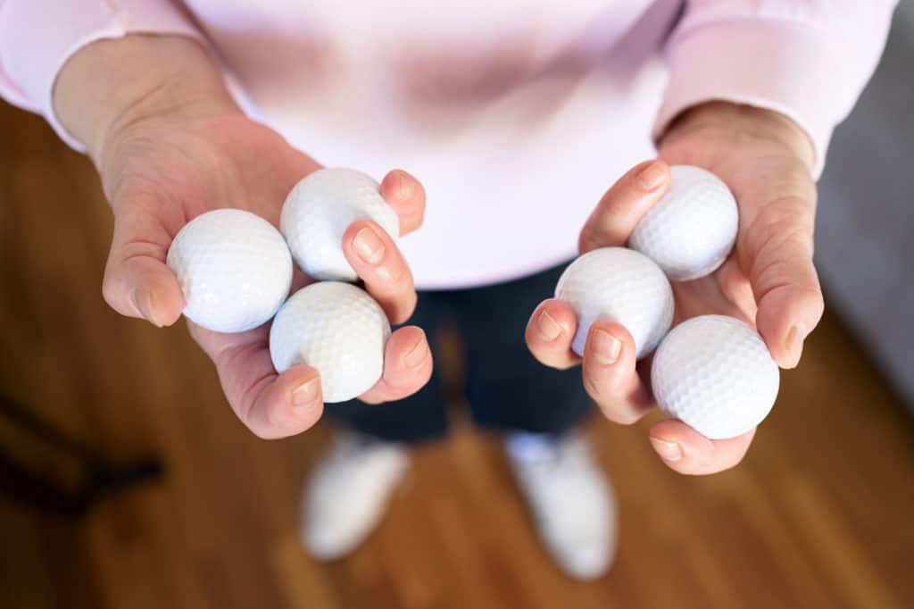 Woman's hands holding several golf balls