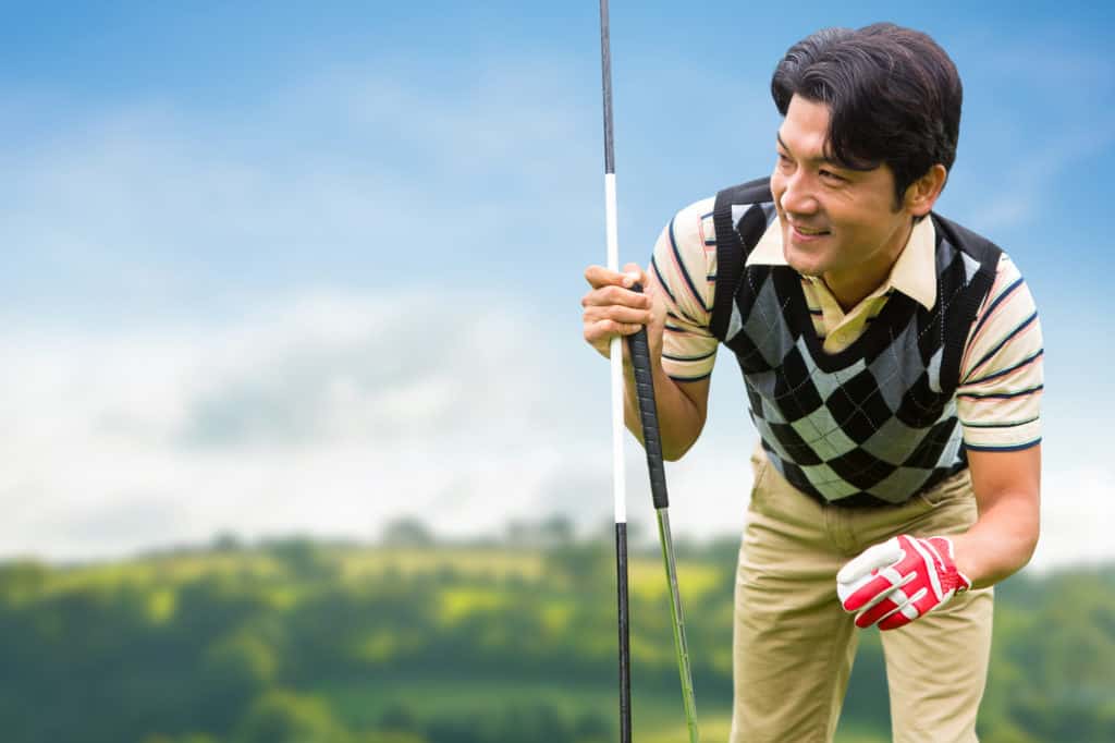 Man with golf equipment against country scene