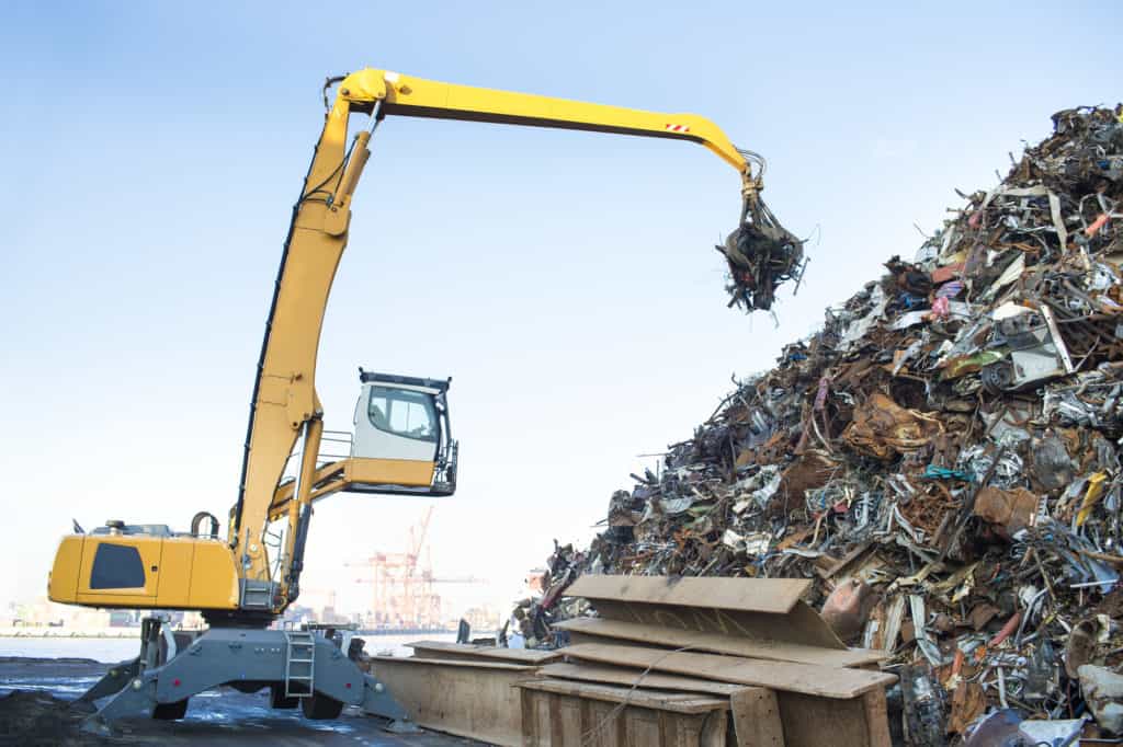 Large tracked excavator working a steel pile at a metal recycle yard