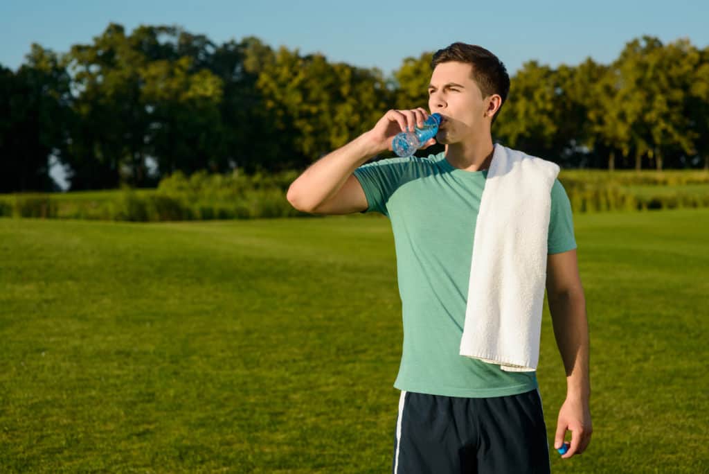 sportsman drinking water with towel