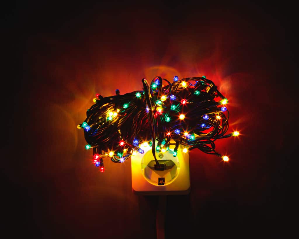 Christmas garland lights bundle on power socket, electricity concept