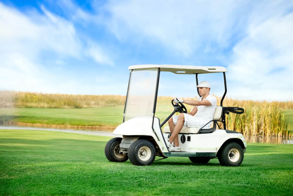 Young man driving golf buggy on golf course