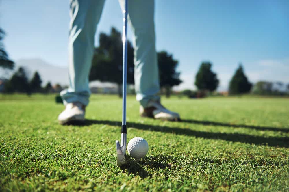 Closeup of golfer with iron hitting tee shot