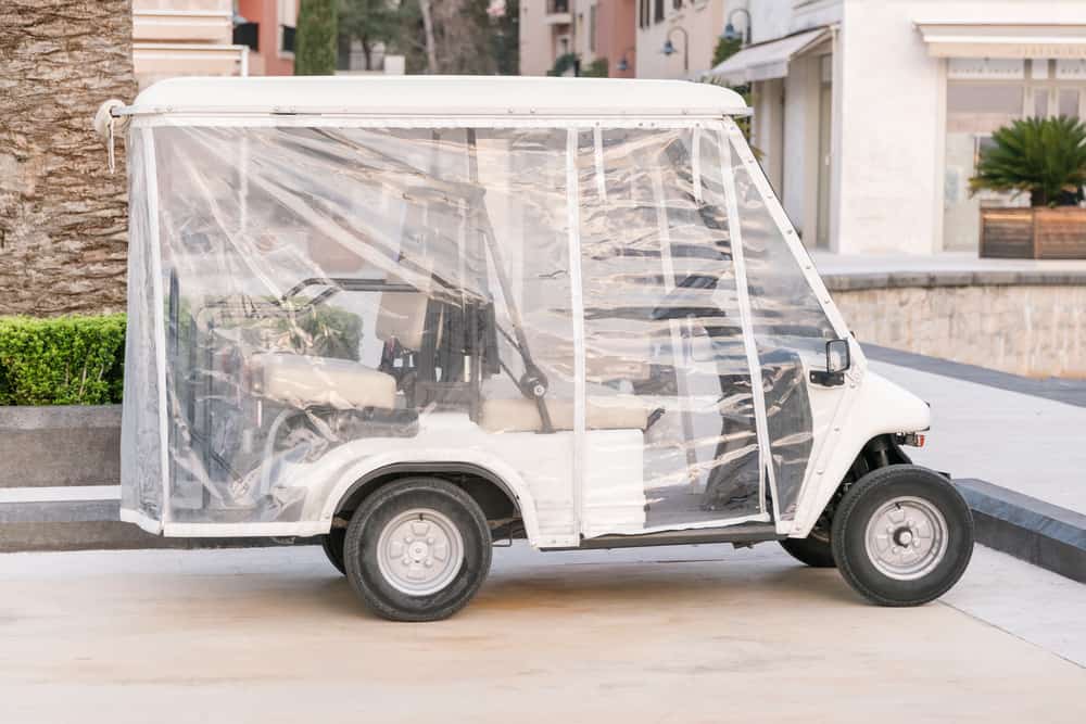 Empty golf car in a cover standing on the street