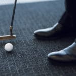 Golf club and golf ball on a gray carpet