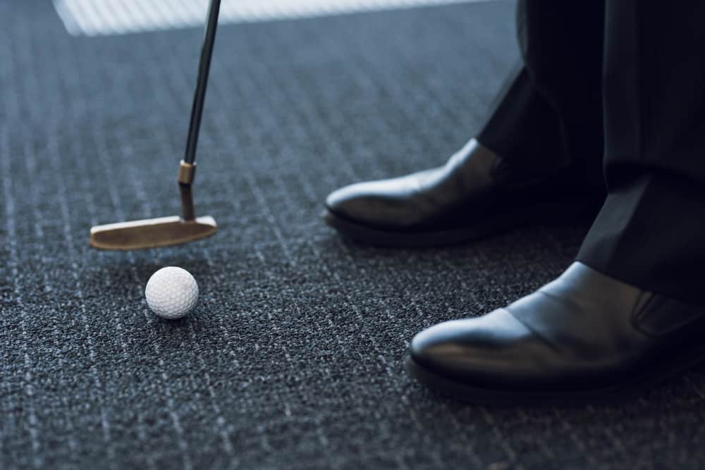 Golf club and golf ball on a gray carpet