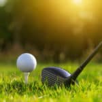 Golf driver and golf balls on a green lawn