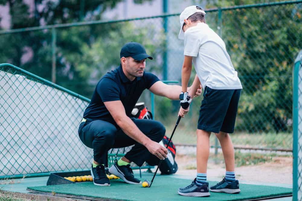 Golf instructor giving game lesson to a young boy