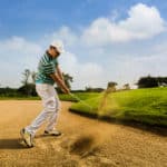Golfer hitting the ball on the sand