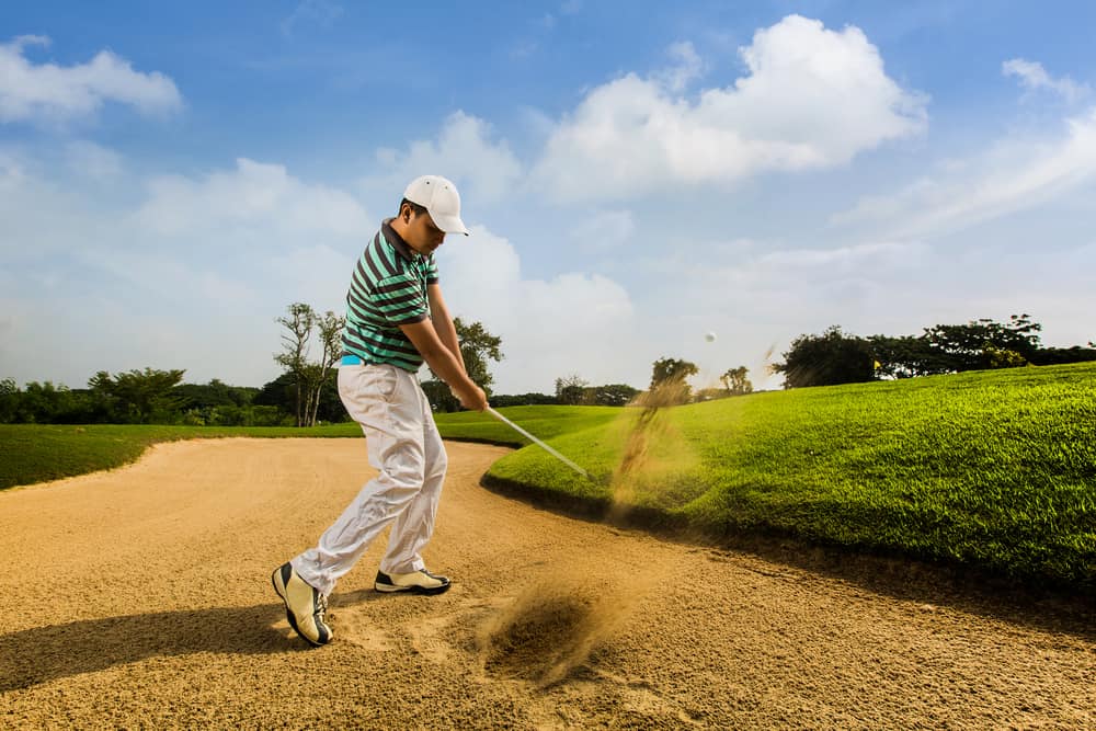 Golfer hitting the ball on the sand