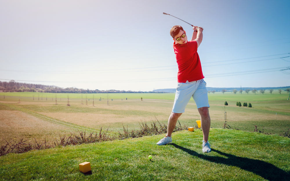 Man playing golf on a golf course in the sun