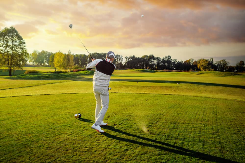 Professional male golf player hitting by driver from tee