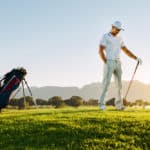 Professional male golfer holding golf club on field