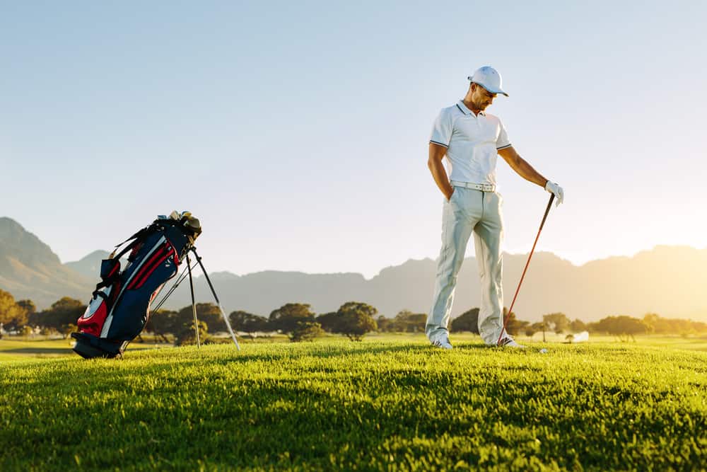 Professional male golfer holding golf club on field