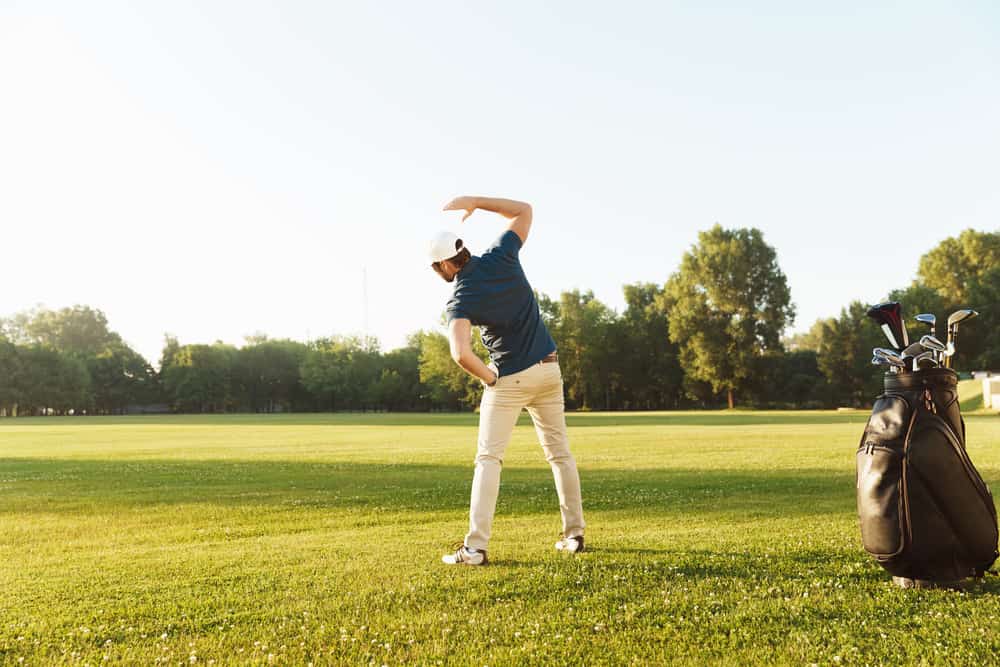 Young male golfer stretching muscles