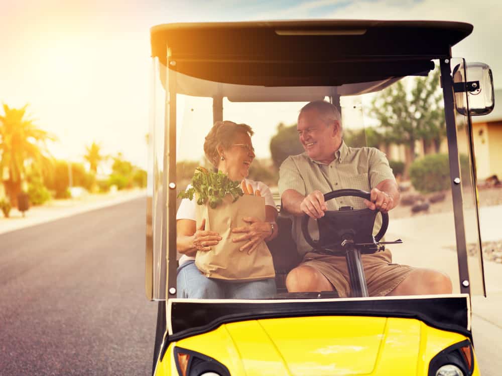 active elderly senior couple getting groceries on golf cart