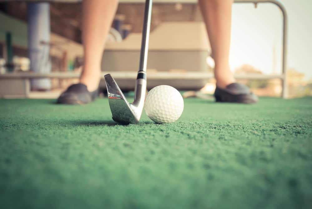 close up girl tee-off at golf driving range