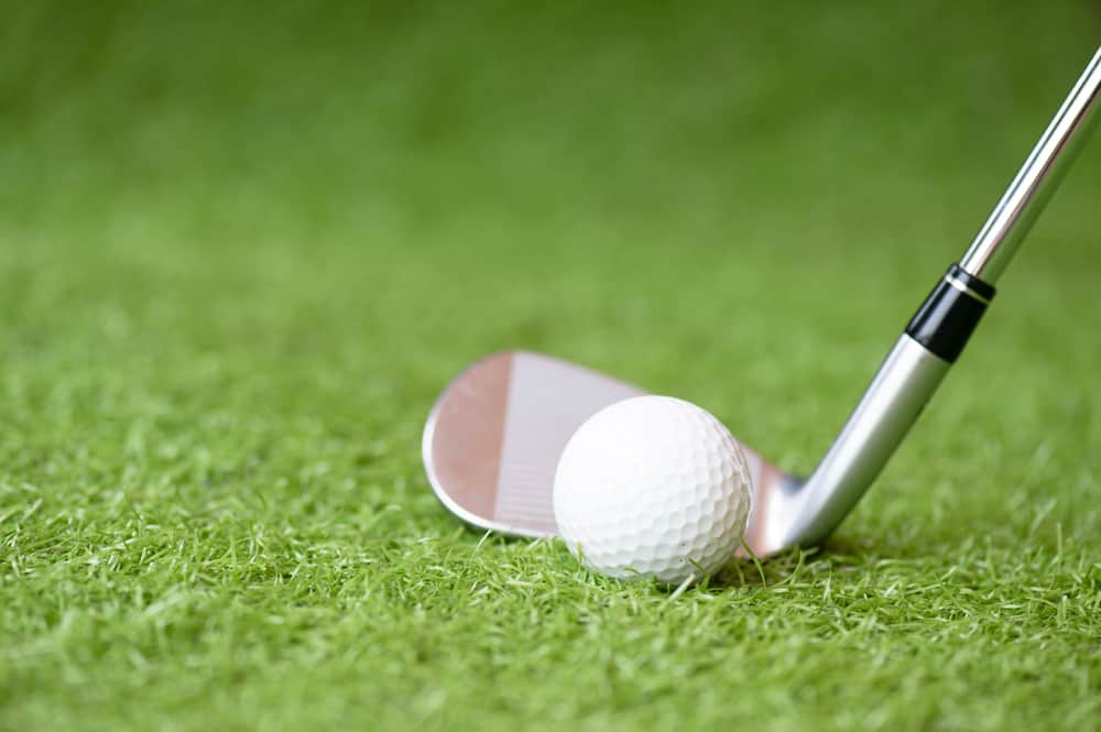 golf club and golf ball on green grass