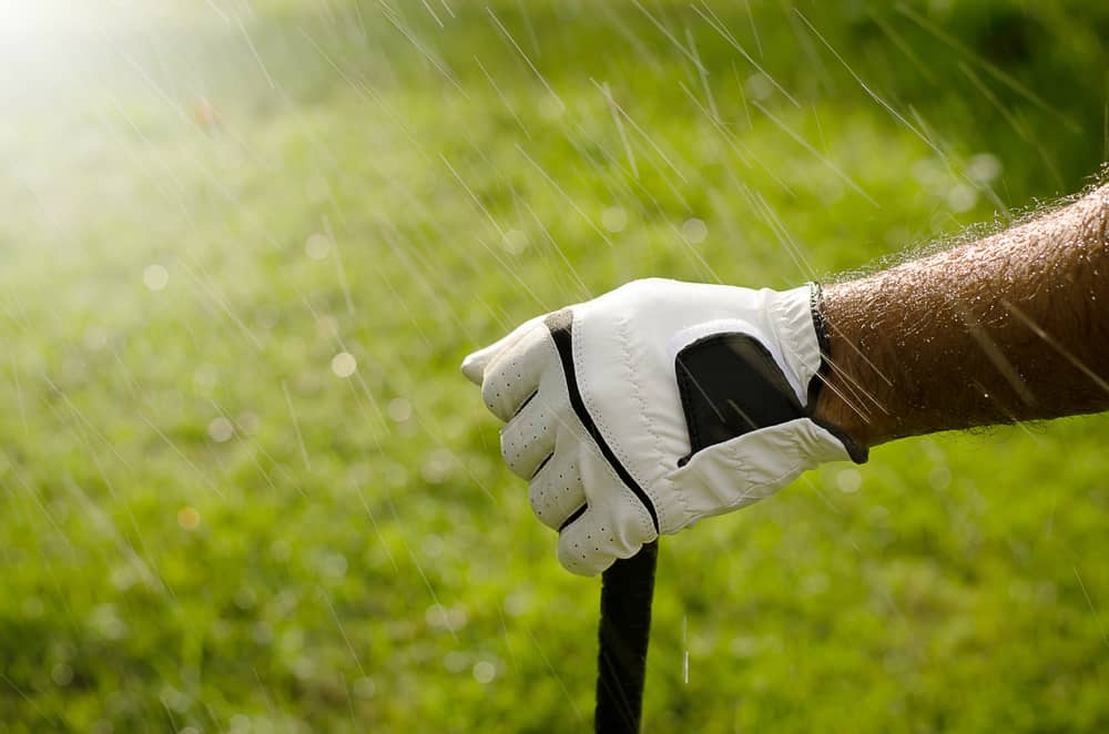 hands of golfers are holding golf clubs by the wet rain