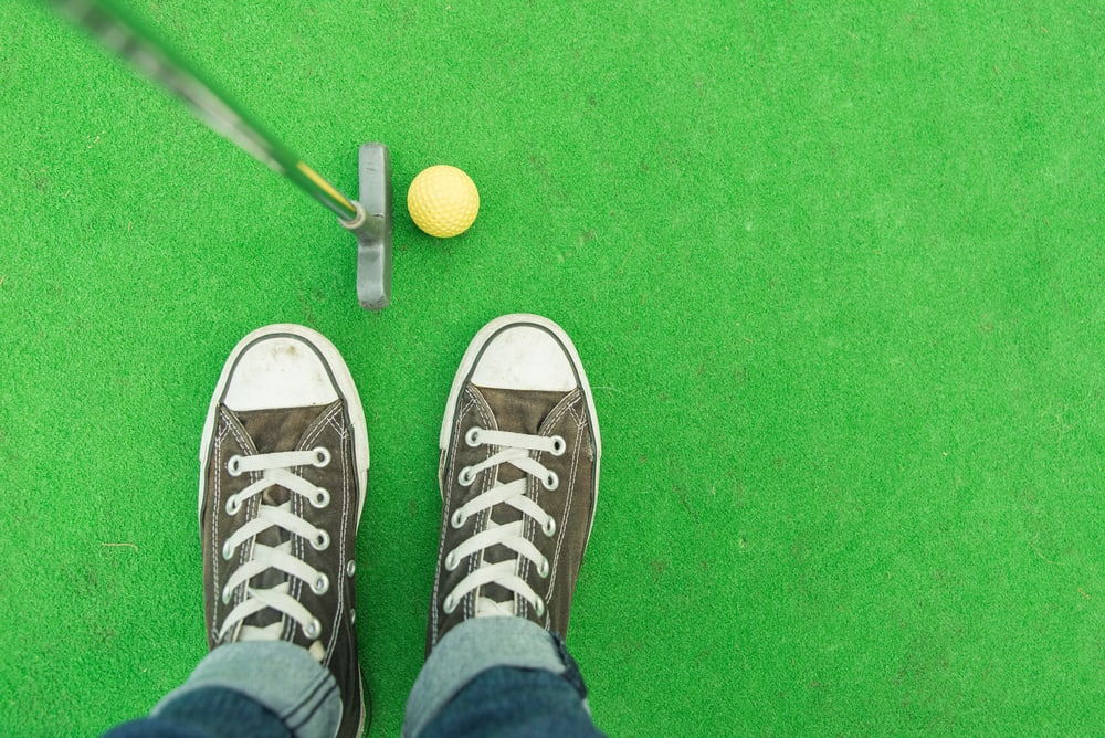 person with club and ball on the mini-golf court