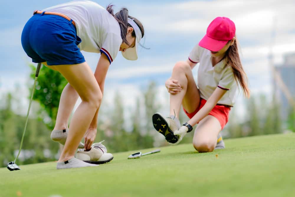 young woman golf player feel uncomfortable in wear of shoe