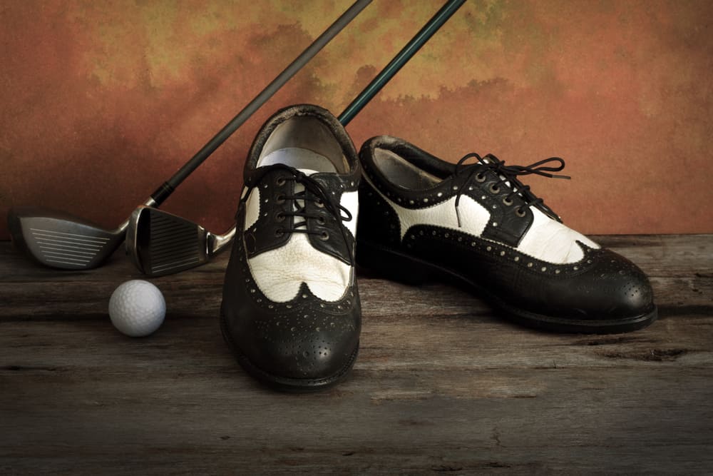 Golf shoes with golf clubs on grunge background