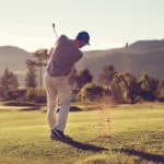 Golfer hitting golf shot with club on course