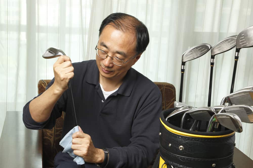 Man cleaning his golf clubs at home