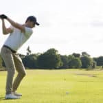 Man hitting driver on a golf course in the sun