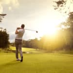 Man playing golf on a golf course in the sun