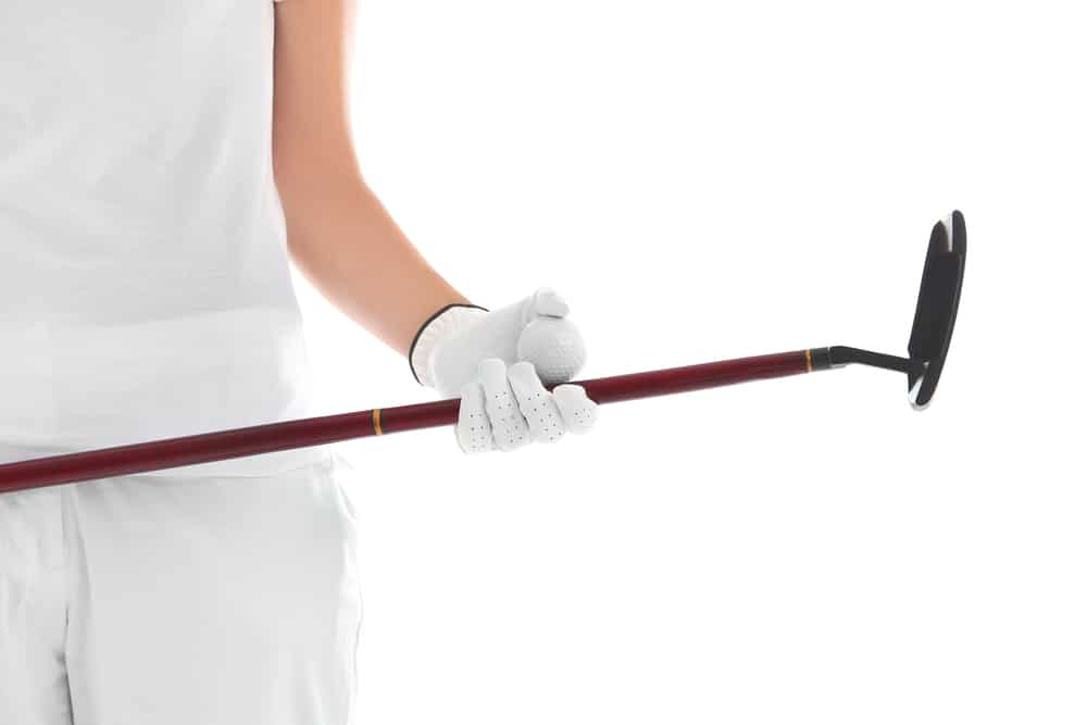 Woman holding golf club and ball