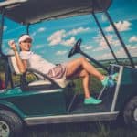 Young cheerful woman driving golf cart