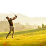 man swing and hitting golf ball