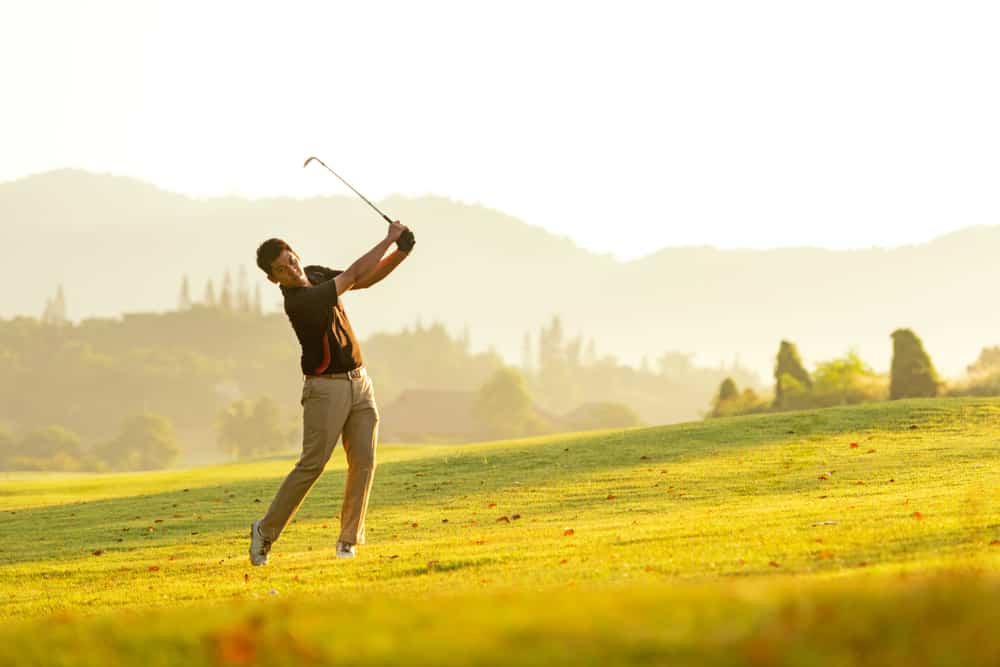 man swing and hitting golf ball